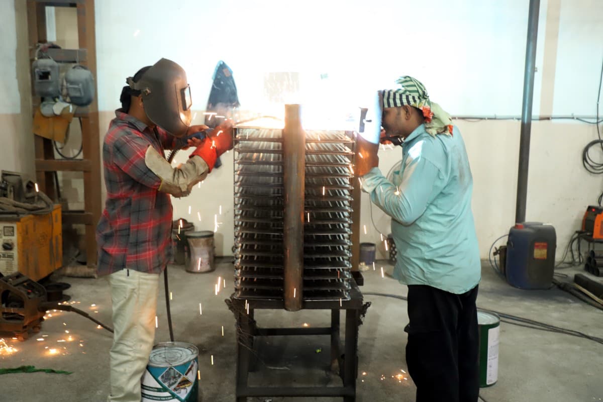 Welder joining radiator panels onto a header